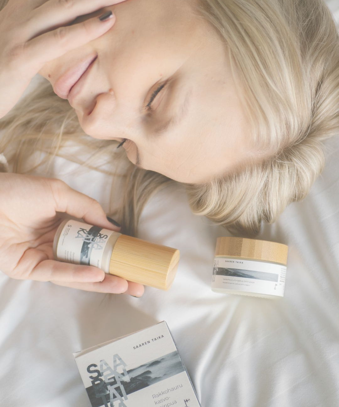 Blonde woman resting with Saaren Taika skincare products, Saaren Taika Journal