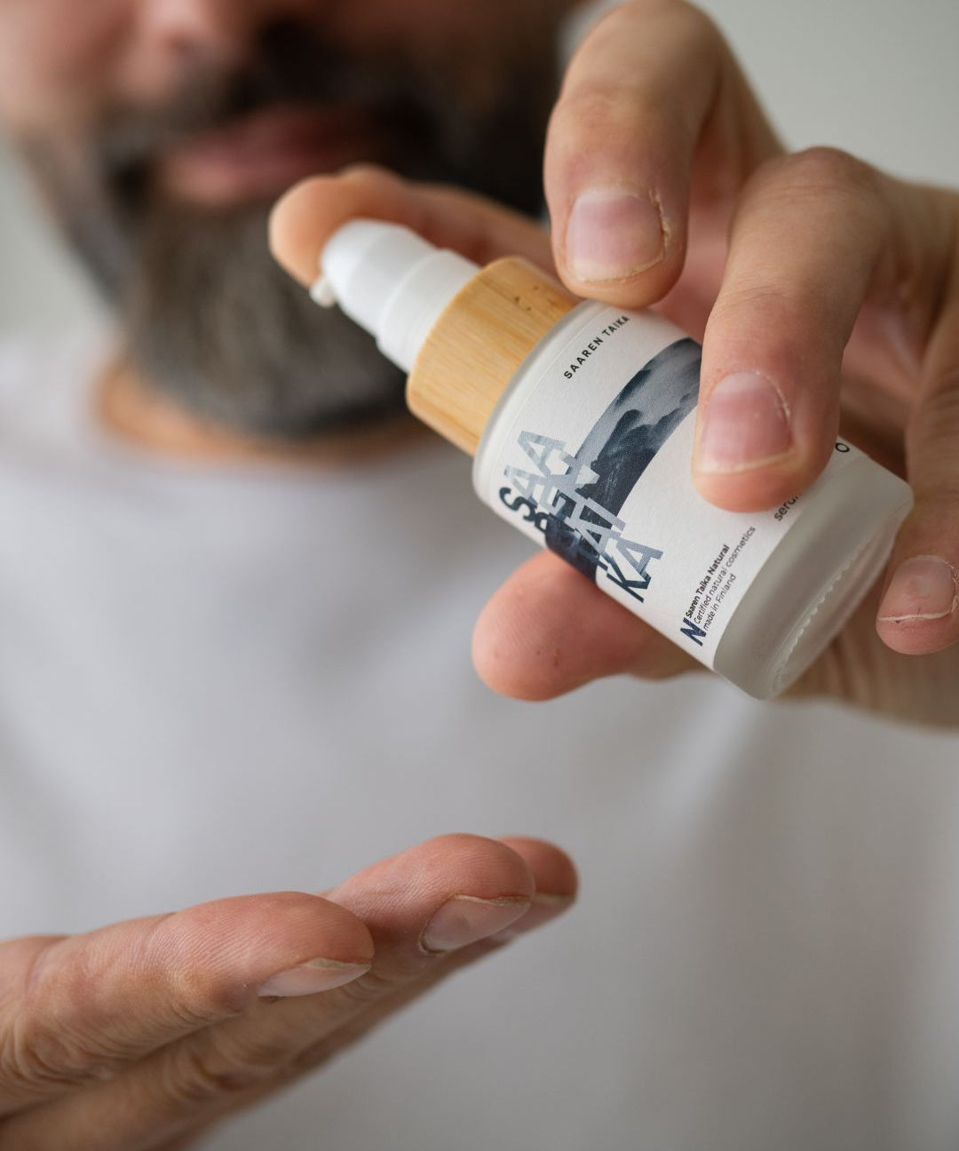 Man applying Saaren Taika face serum to his hand, skincare for acne-prone skin