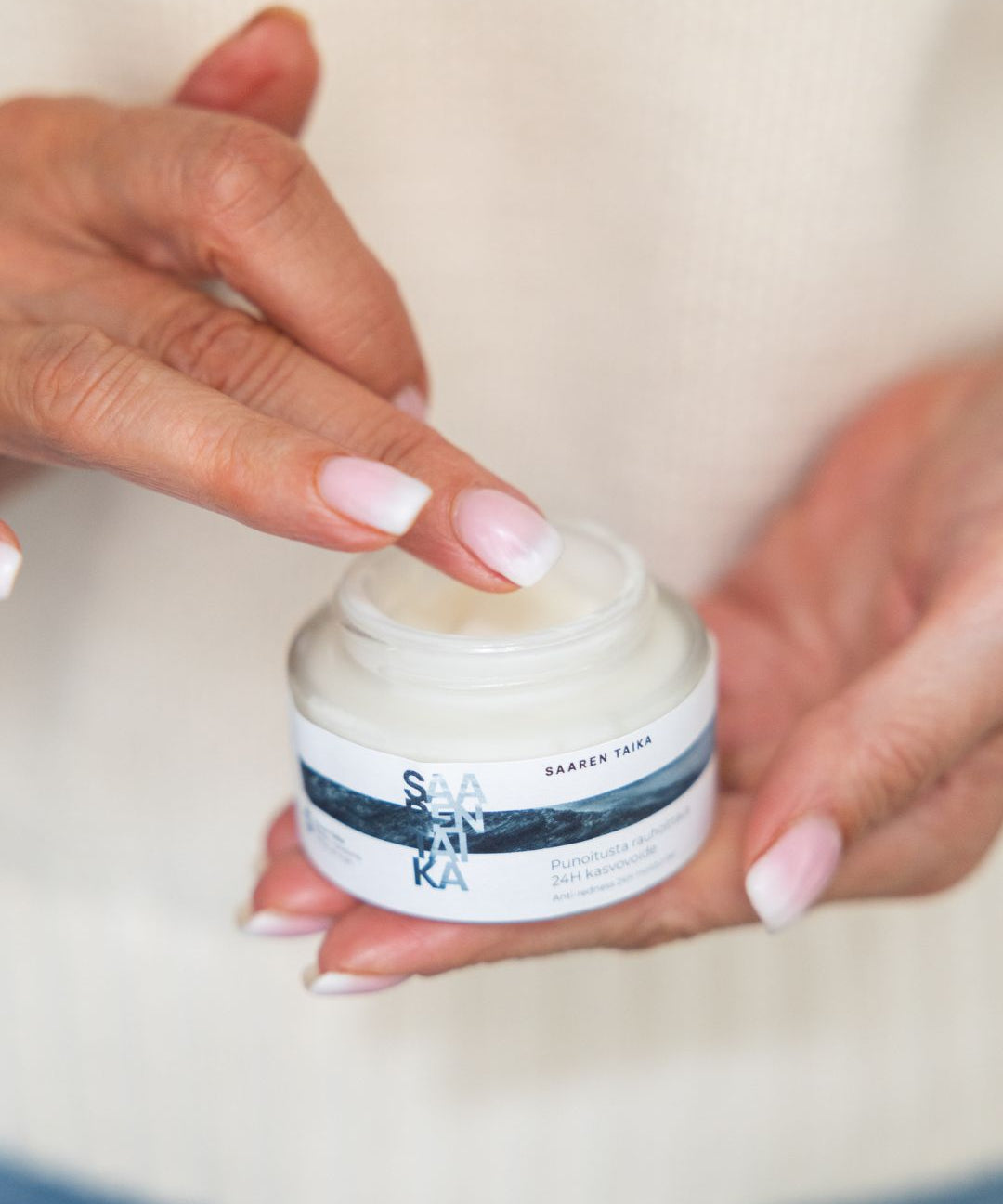 Hands holding a jar of Saaren Taika face cream, skincare for redness-prone skin